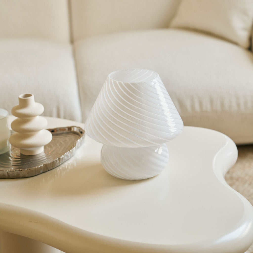 White ceramic sculpture on a white coffee table with a beige sofa in the background