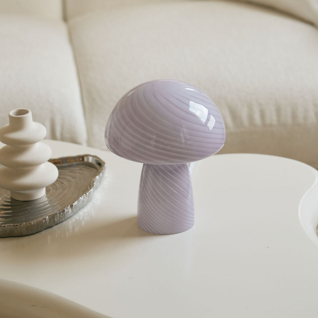 Purple mushroom-shaped lamp on a white table with a blurred background