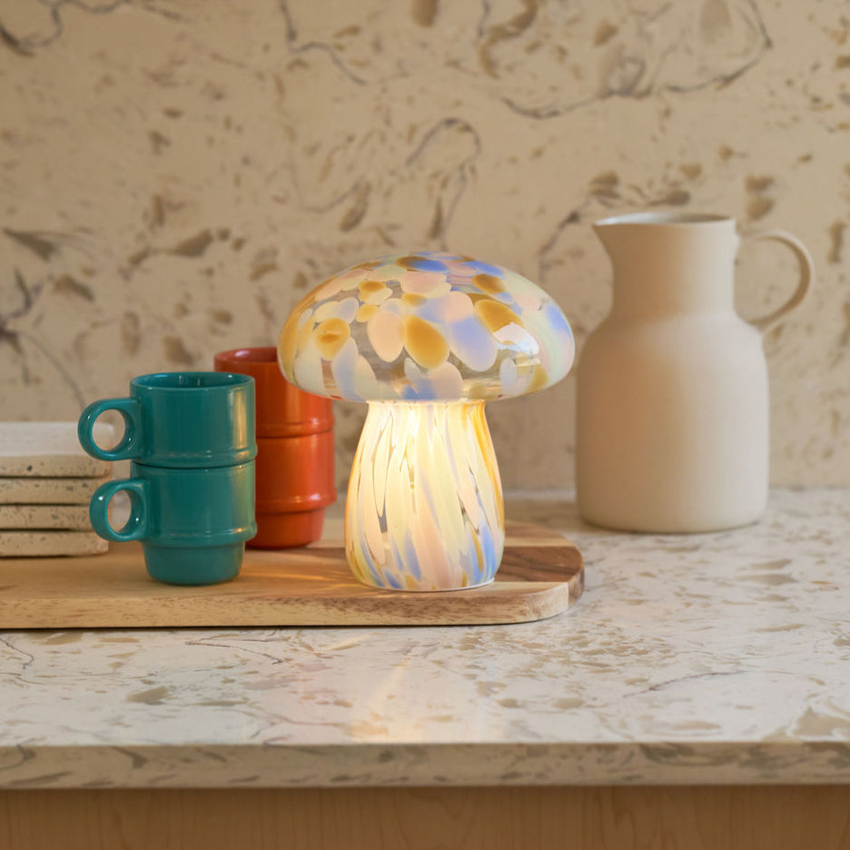 Colorful mushroom-shaped lamp on a wooden surface with a neutral background