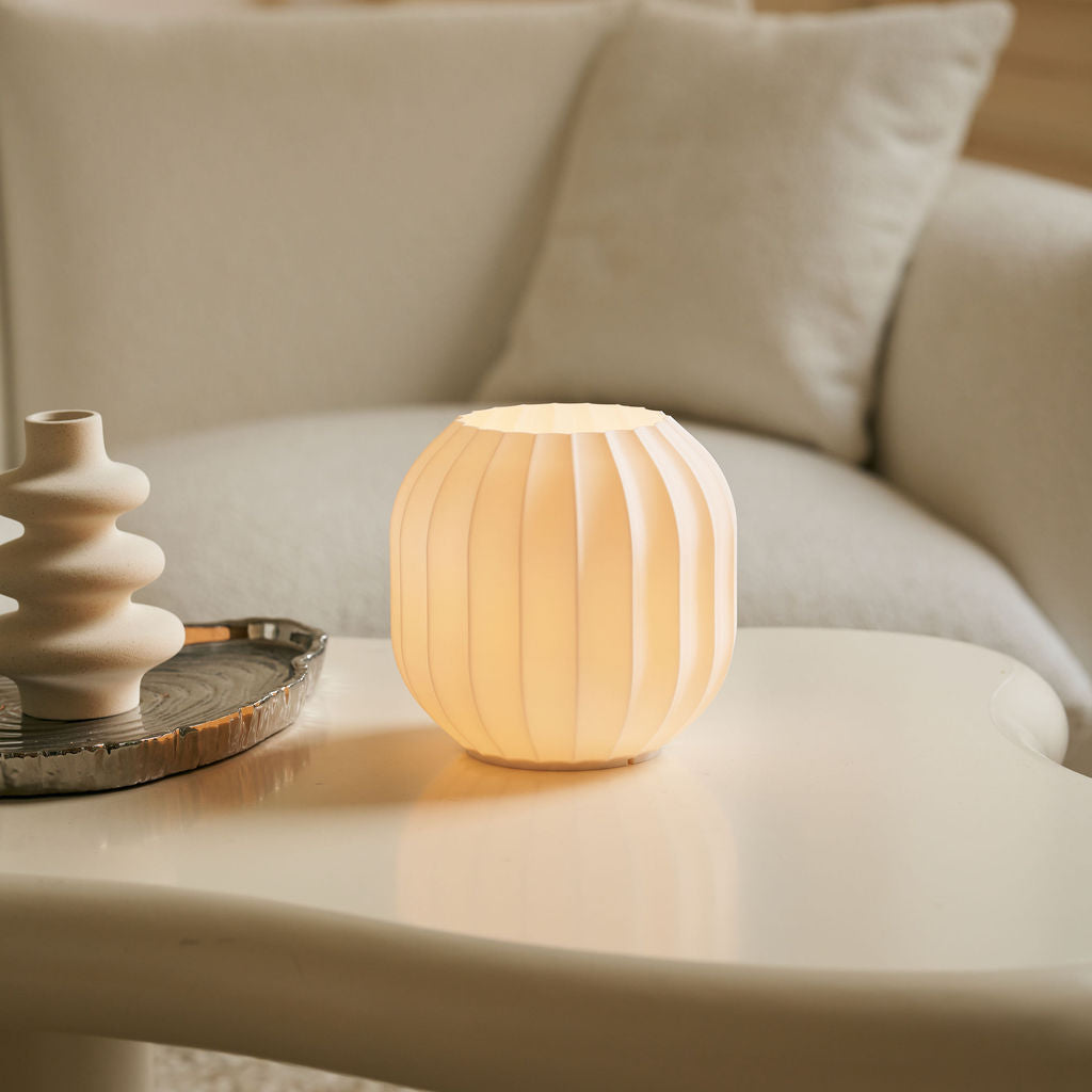 Light-colored lamp on a table with a blurred sofa in the background