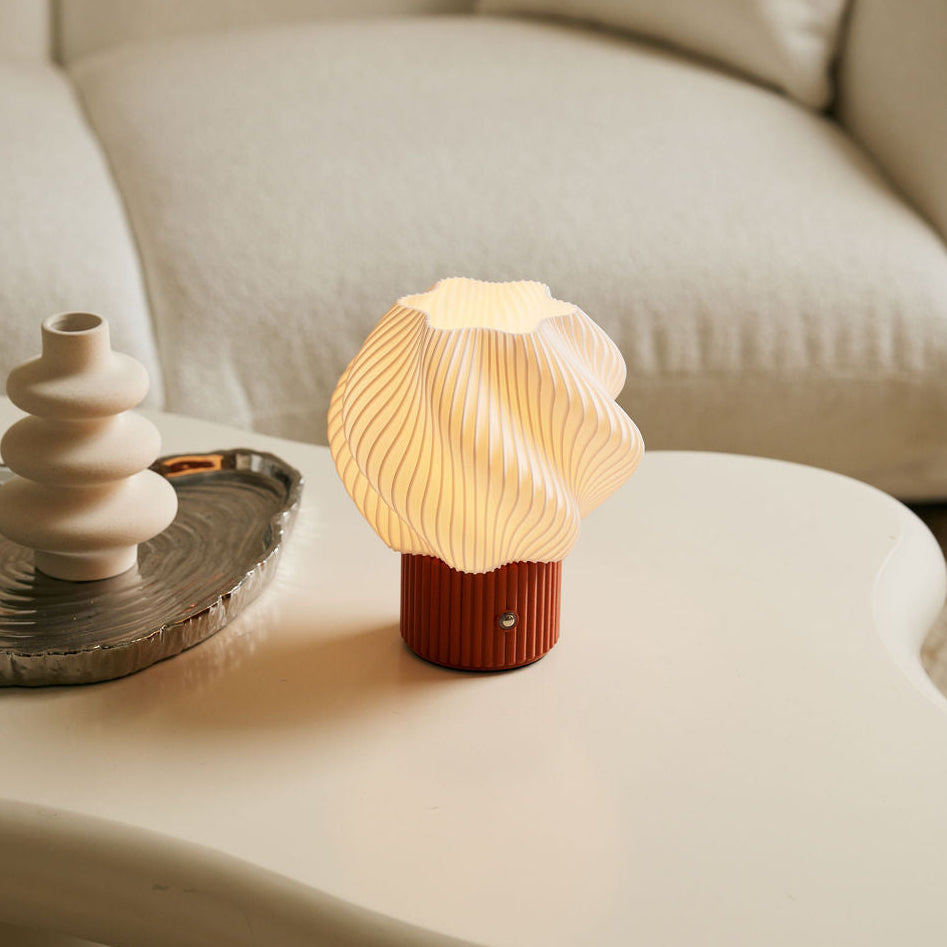 Shell-shaped lamp on a white coffee table with a beige sofa in the background